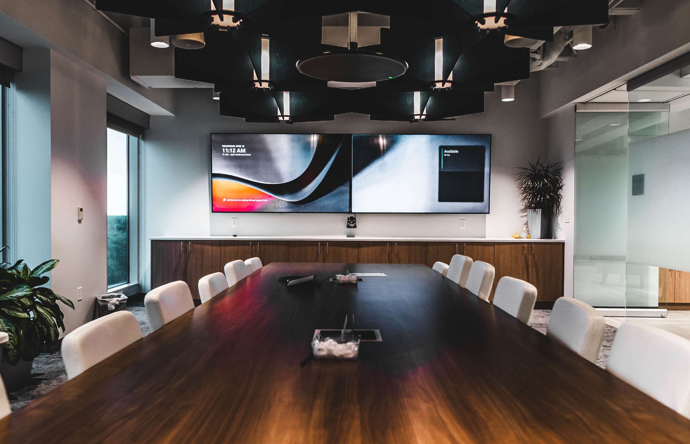 Leeward’s conference room: a long wood table, dual wall displays, and ceiling microphones.