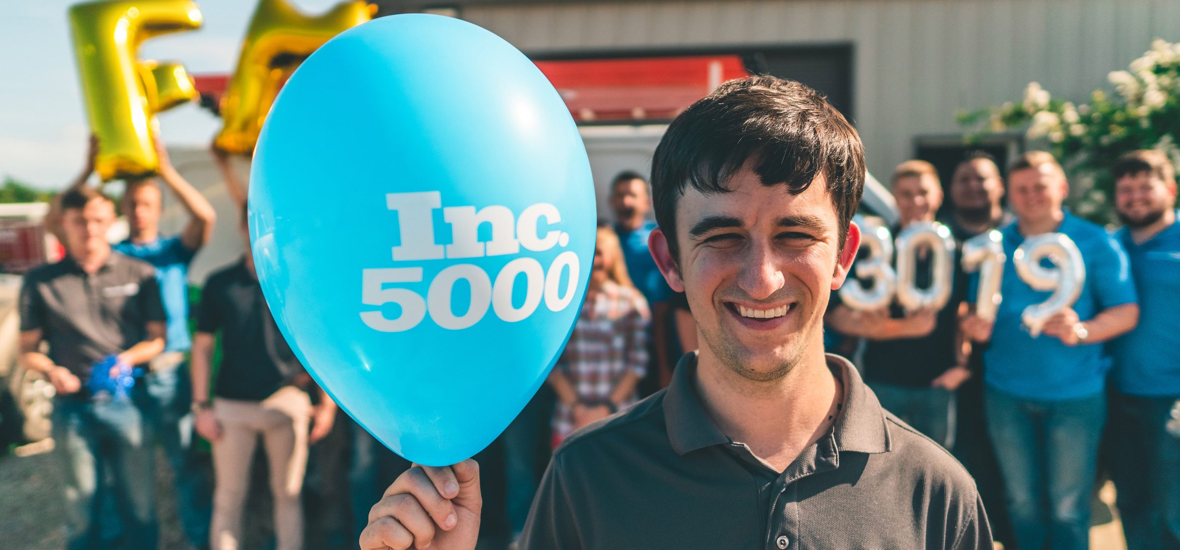 The FM team outside, holding an Inc. 5000 balloon.